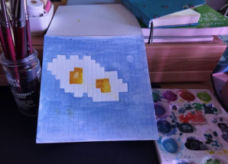 photo of pixel watercolor sketchbook on page 1, a couple of pixel art fried eggs